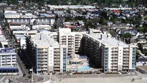 A coastal hotel with multiple high-rise buildings, a central pool, and a beach area. - Luxury Vacation Condos at Seaside Oceanfront Resort (Seaside)