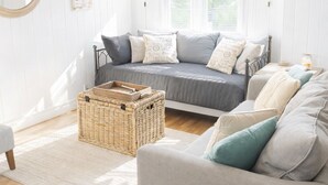 Une chambre confortable avec un lit, un canapé, un panier en osier et un miroir.