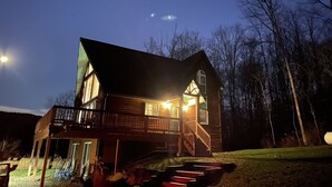 A two-story wooden house with a balcony, a front porch, and a staircase leading to the second floor. - Private 4-bedroom chalet with breathtaking views! (Great Valley)