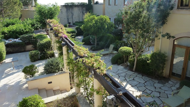 Une cour dallée de pierres, un espace de repos abrité et une végétation luxuriante.