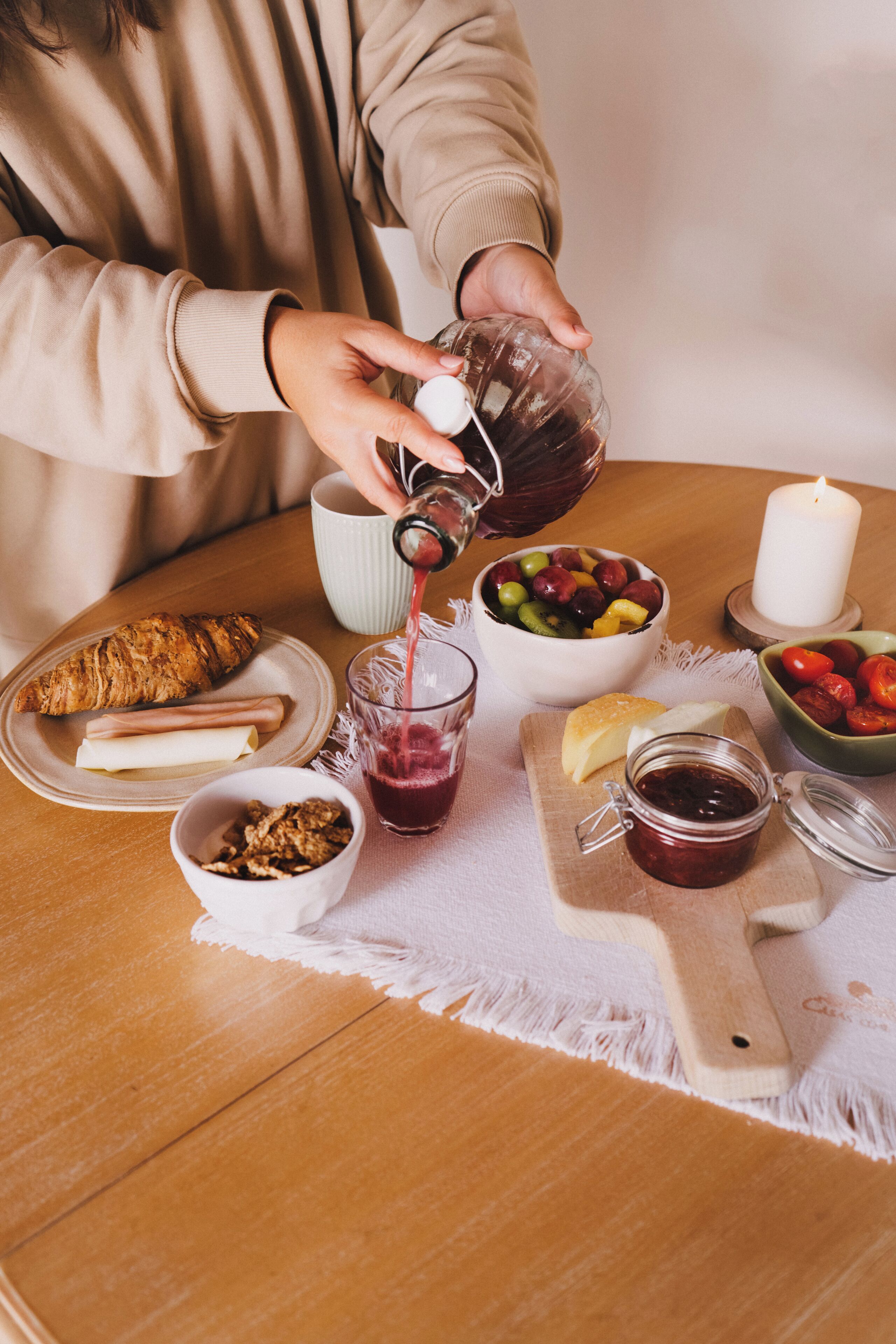 Een ontbijtje met een croissant, kaas en een schaal fruit op een houten tafel.