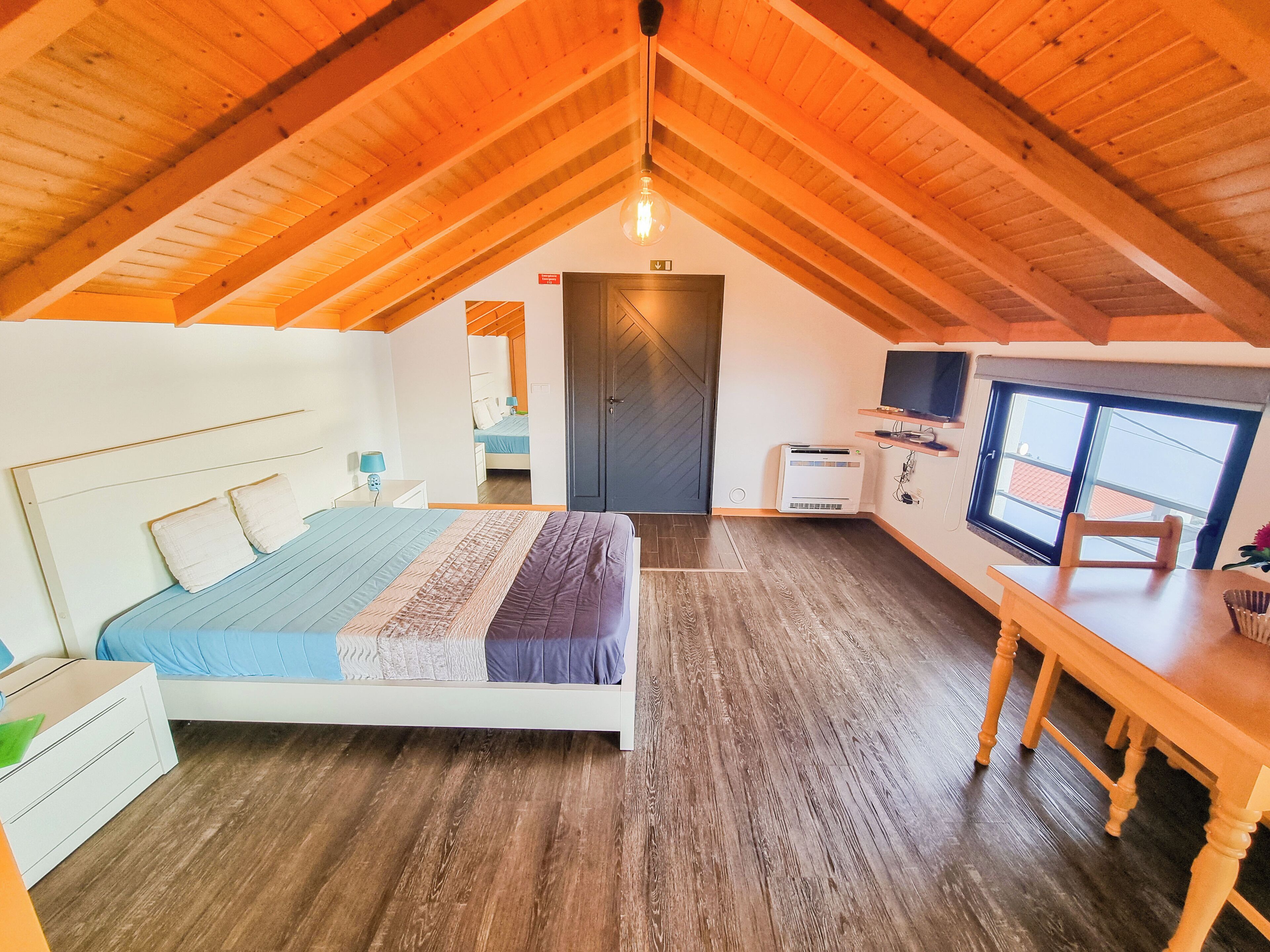 A bedroom with a bed, bedside tables, a desk, and a television.