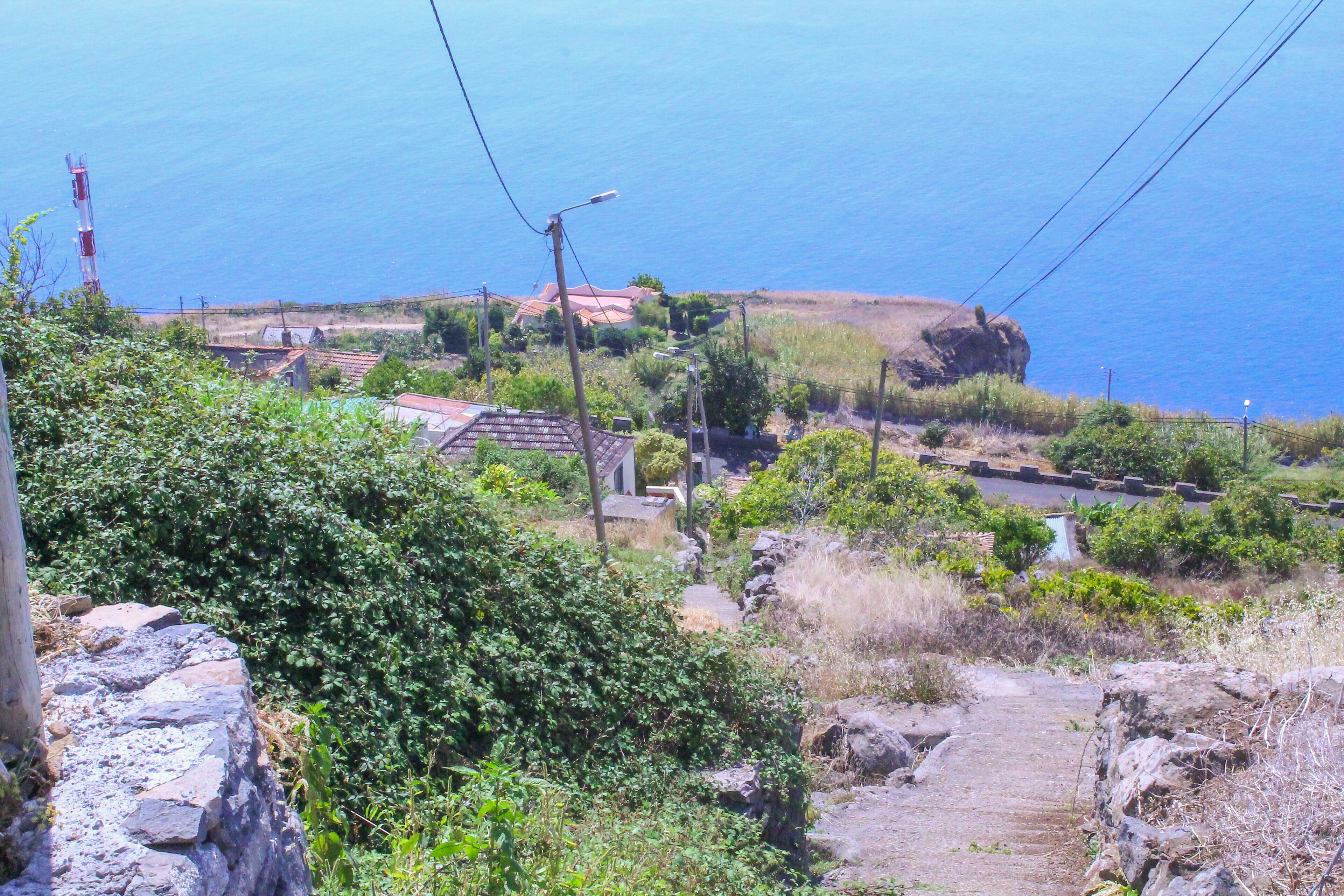 A coastal village with traditional houses, a rocky path, and a view of the sea.