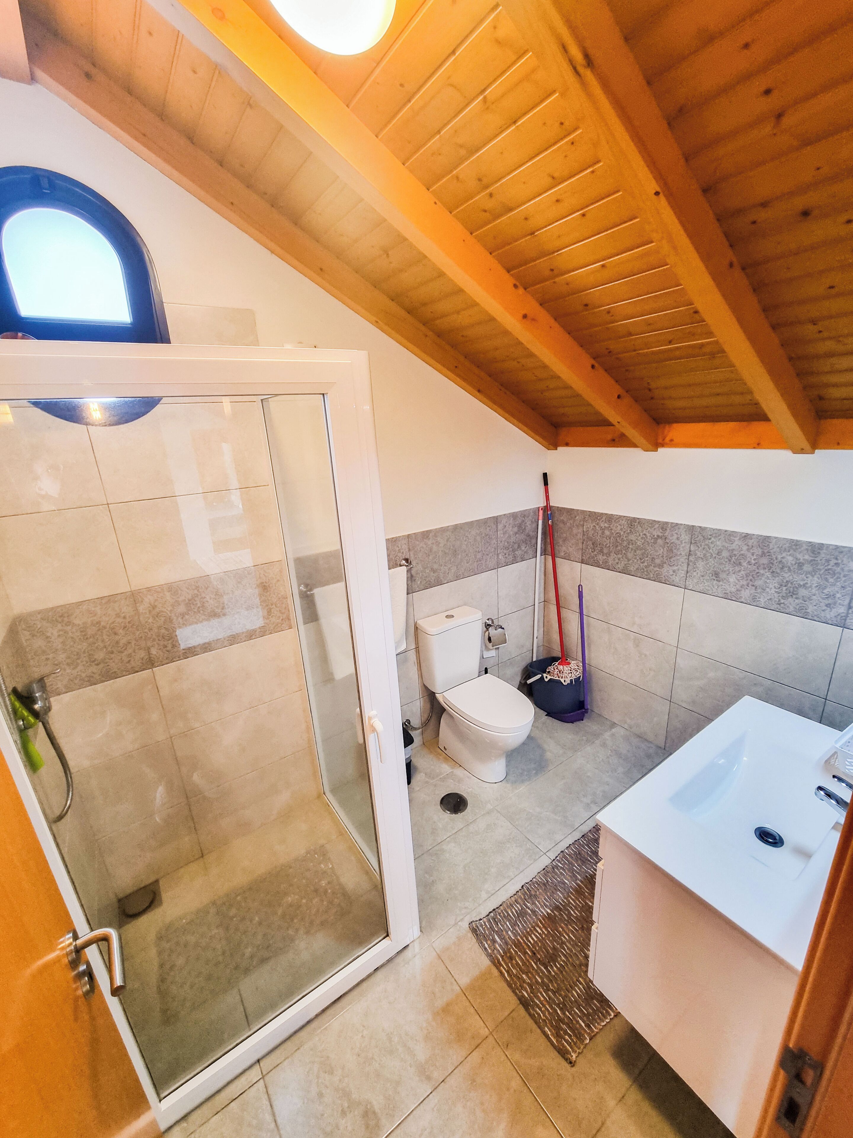 A bathroom with a glass shower enclosure, a toilet, and a sink.