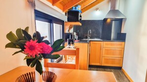 A kitchen with wooden cabinets, a stainless steel sink, and a black countertop. - Studio One | Ocean View | Perfect Budget Couple's Retreat with Free WIFI (Fajã da Ovelha)