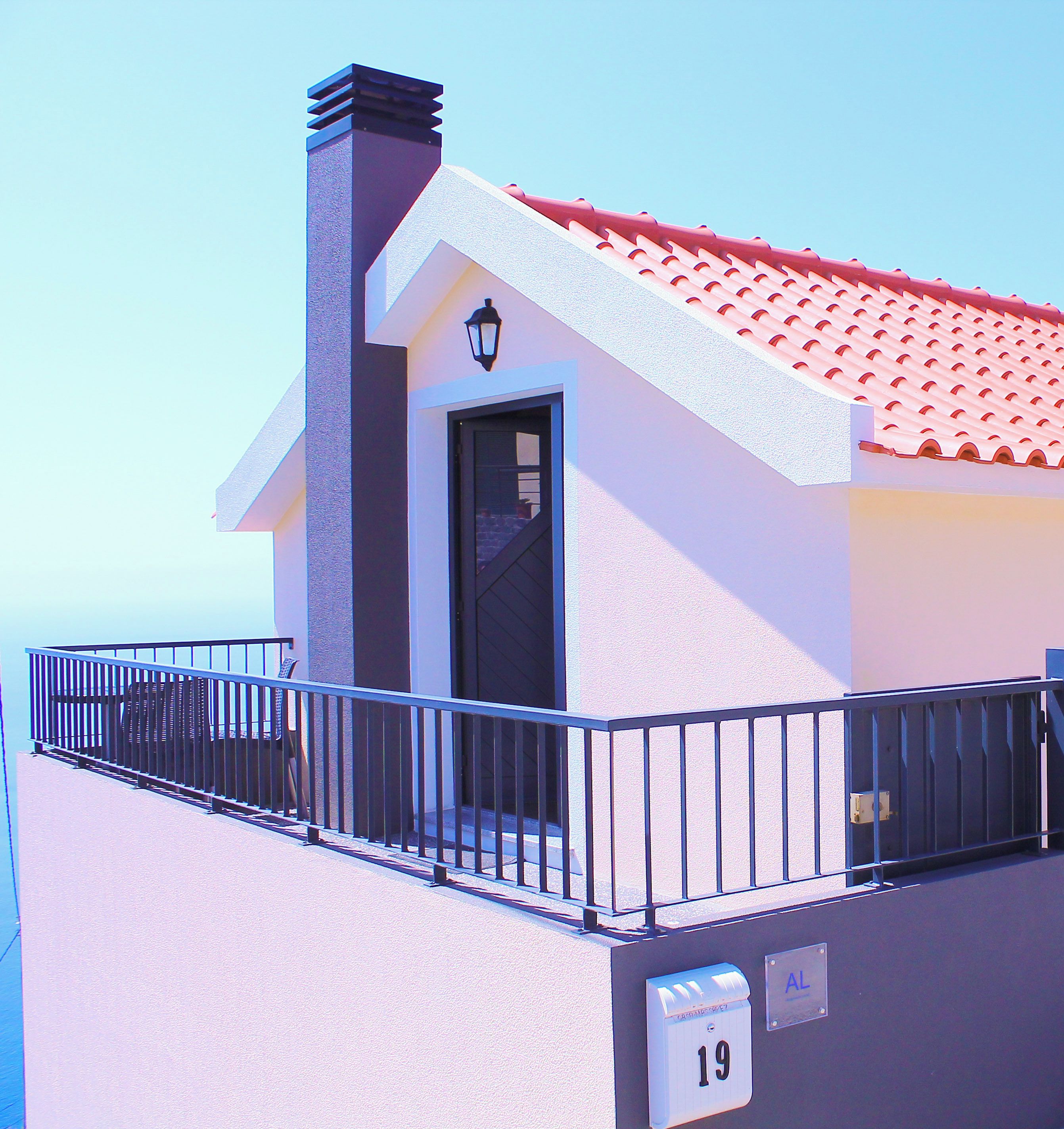 A modern building with a red-tiled roof, a balcony with a railing, and a sign indicating free Wi-Fi and parking.