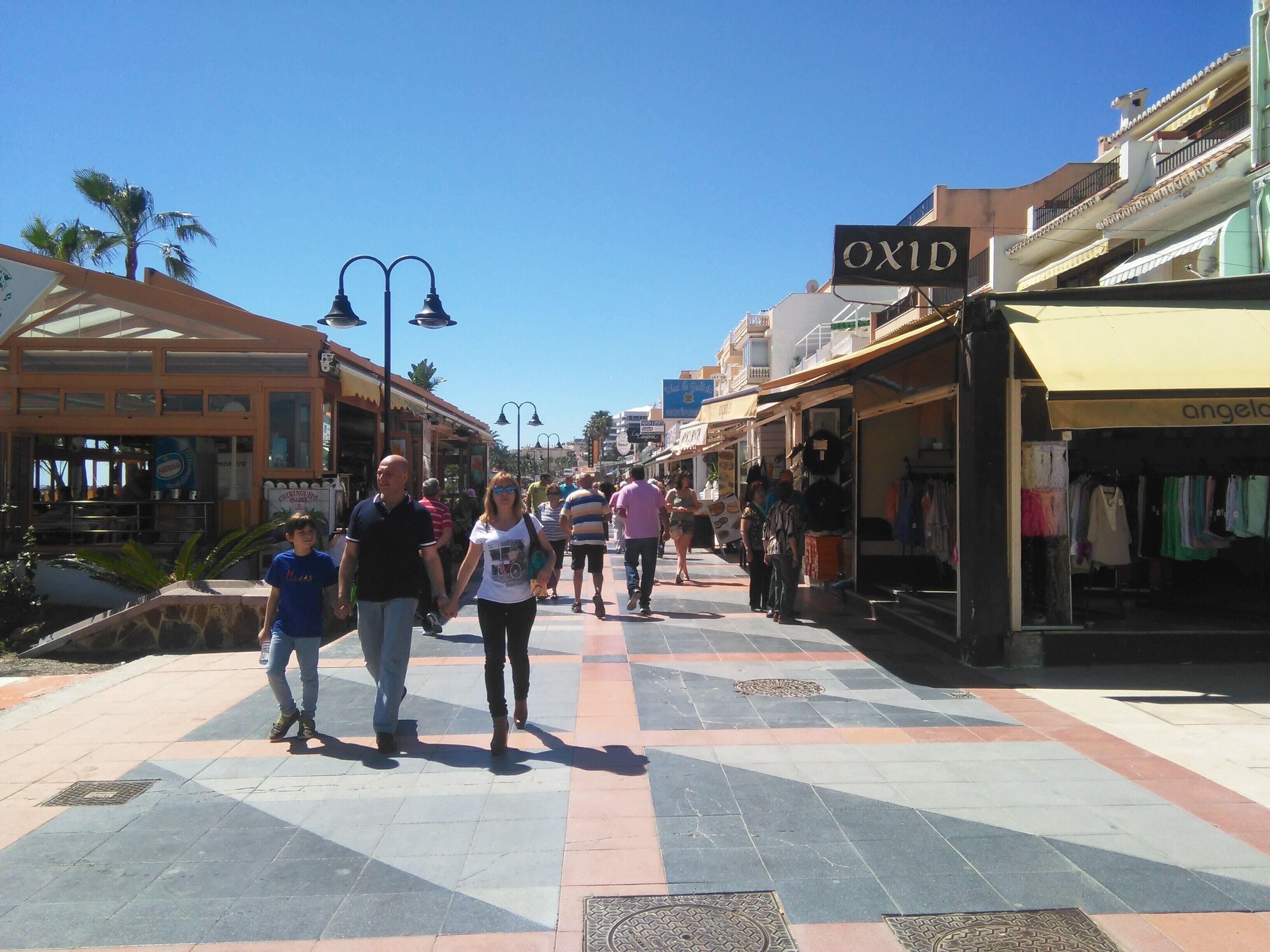 A pedestrian street with shops and outdoor seating areas.
