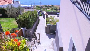 Un edificio residencial con una escalera que conduce a un balcón con vistas a la costa.