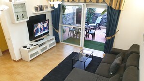 En stue med sofa, sofabord, fjernsyn og et glaskab med vinglas.