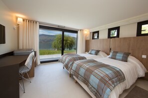A bedroom with two beds, a desk, and a chair. There is a large window with a view of a lake and mountains. - Villa Bagatelle 5 stars Vision Luxe 10 people 5 bedrooms Annecy (Veyrier-du-Lac)