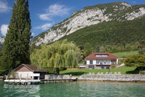 A lakeside property with a house, dock, and mountain backdrop.