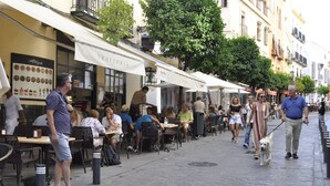 Un caffè all'aperto con tavoli, sedie e una bacheca dei menu, mentre un cane passeggia al guinzaglio.