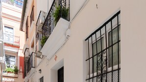Una stretta via cittadina con edifici bianchi, grate metalliche nere alle finestre e un pavimento piastrellato.