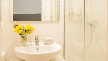 A bathroom with a white sink, a mirror above it, and a glass shower enclosure.