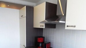 Eine kleine Küche mit Herd, Backofen und Kaffeemaschine auf der Arbeitsfläche.
