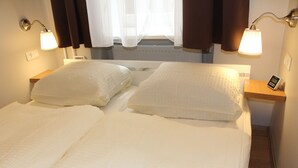 Un letto matrimoniale con lenzuola bianche e due comodini, ognuno con una lampada.