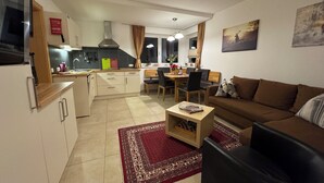 A modern apartment with a kitchen, dining area, and living room. It includes a sofa, a coffee table, and a rug.