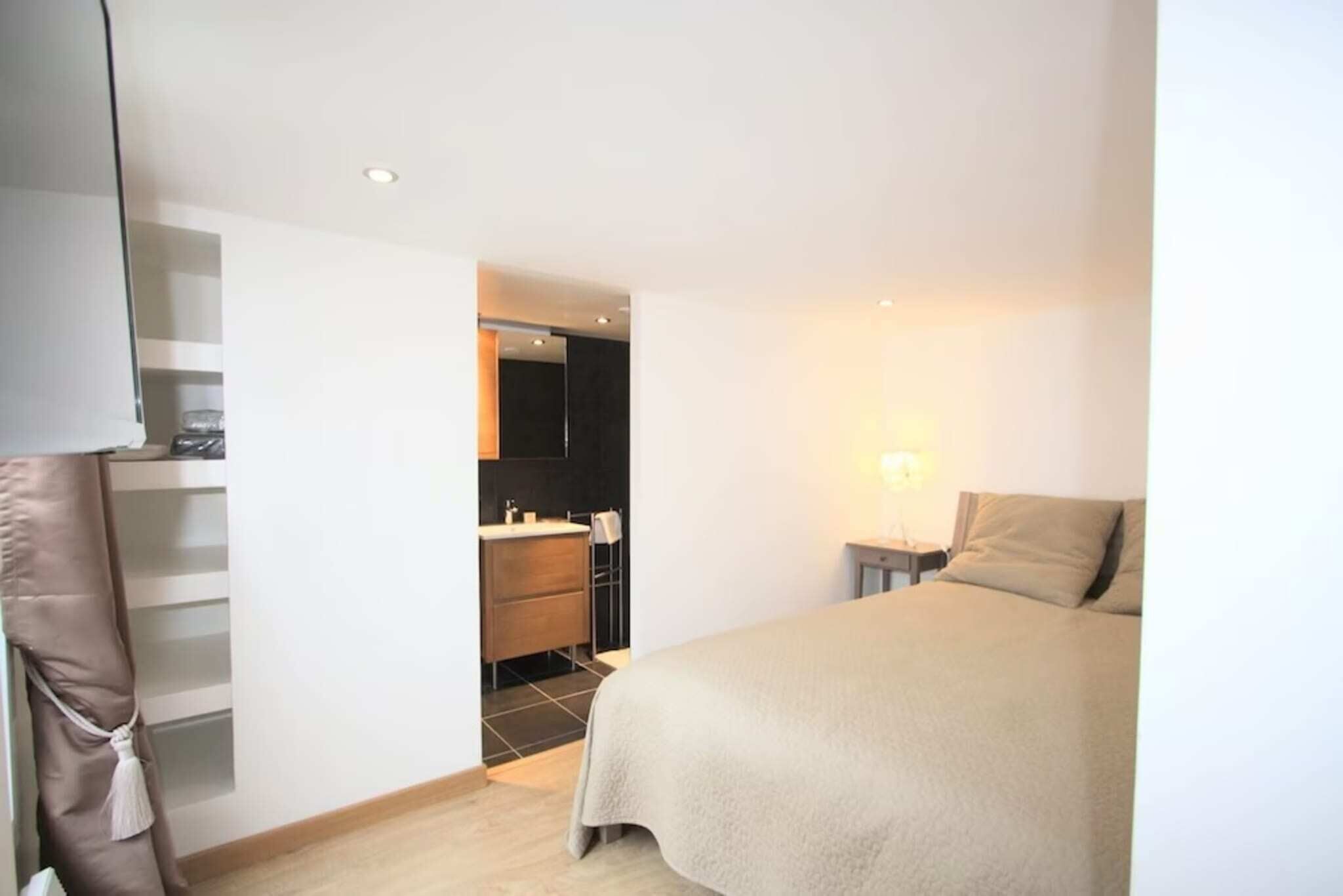 A bedroom with a bed, a bedside table, a nightstand, and a closet.