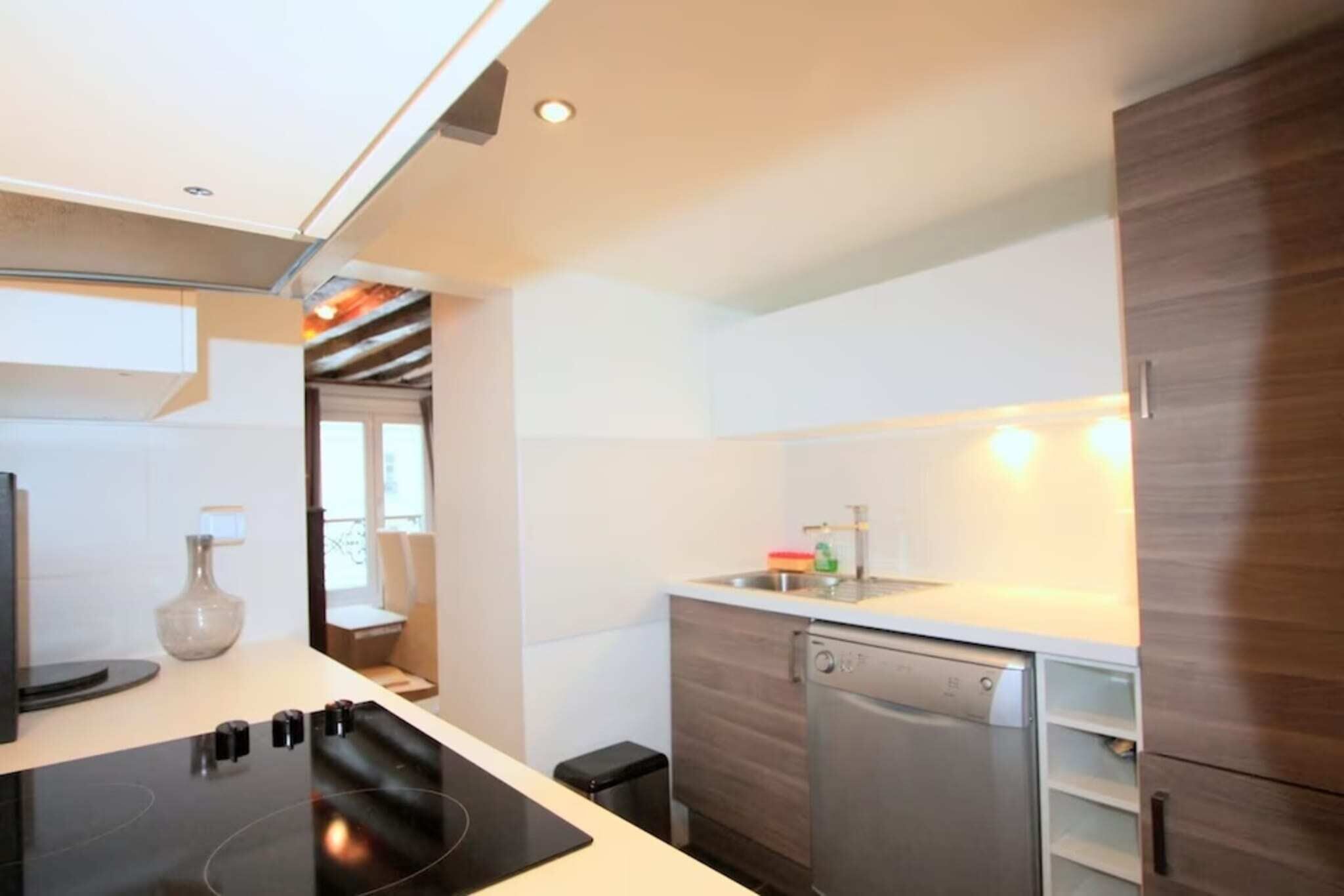 A modern kitchen with a built-in stove, a dishwasher, and a small window.