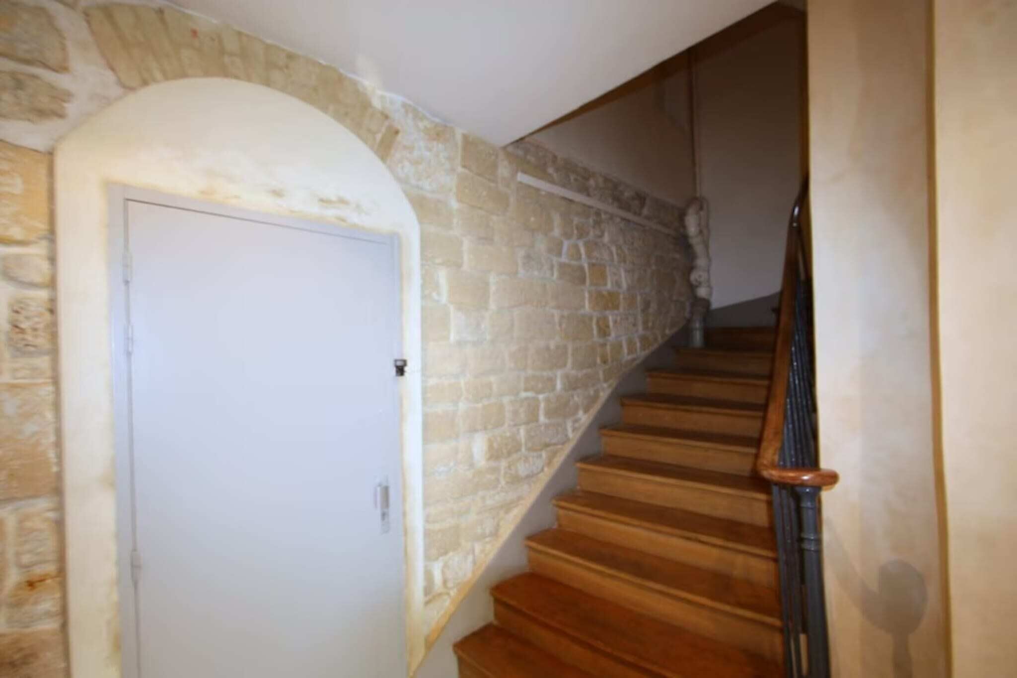 A staircase with wooden steps and a stone wall.