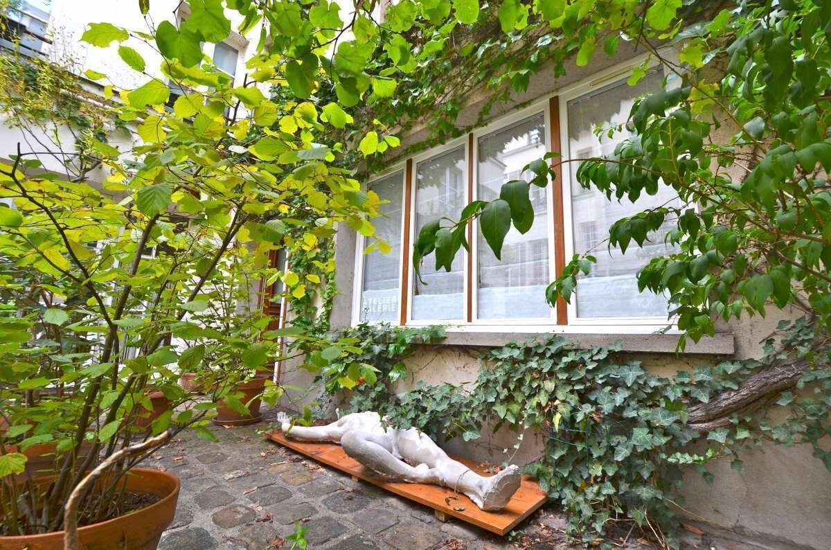 Un patio con plantas en macetas, una escultura y un edificio con ventanas grandes.