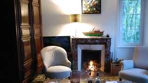 Un salon chaleureux avec une cheminée, des fauteuils confortables et une table mise pour le repas.