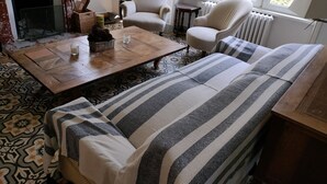 Un salon chaleureux avec un sol à motifs, une table basse en bois, un canapé à rayures et une cheminée.
