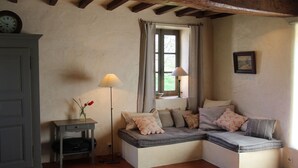 Une pièce chaleureuse avec un banc intégré, une petite table sur laquelle est posé un vase, et une lampe.