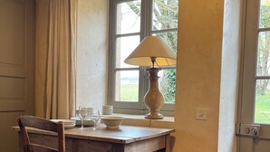 Un coin repas avec une table en bois, une chaise, une lampe et une fenêtre avec des rideaux.