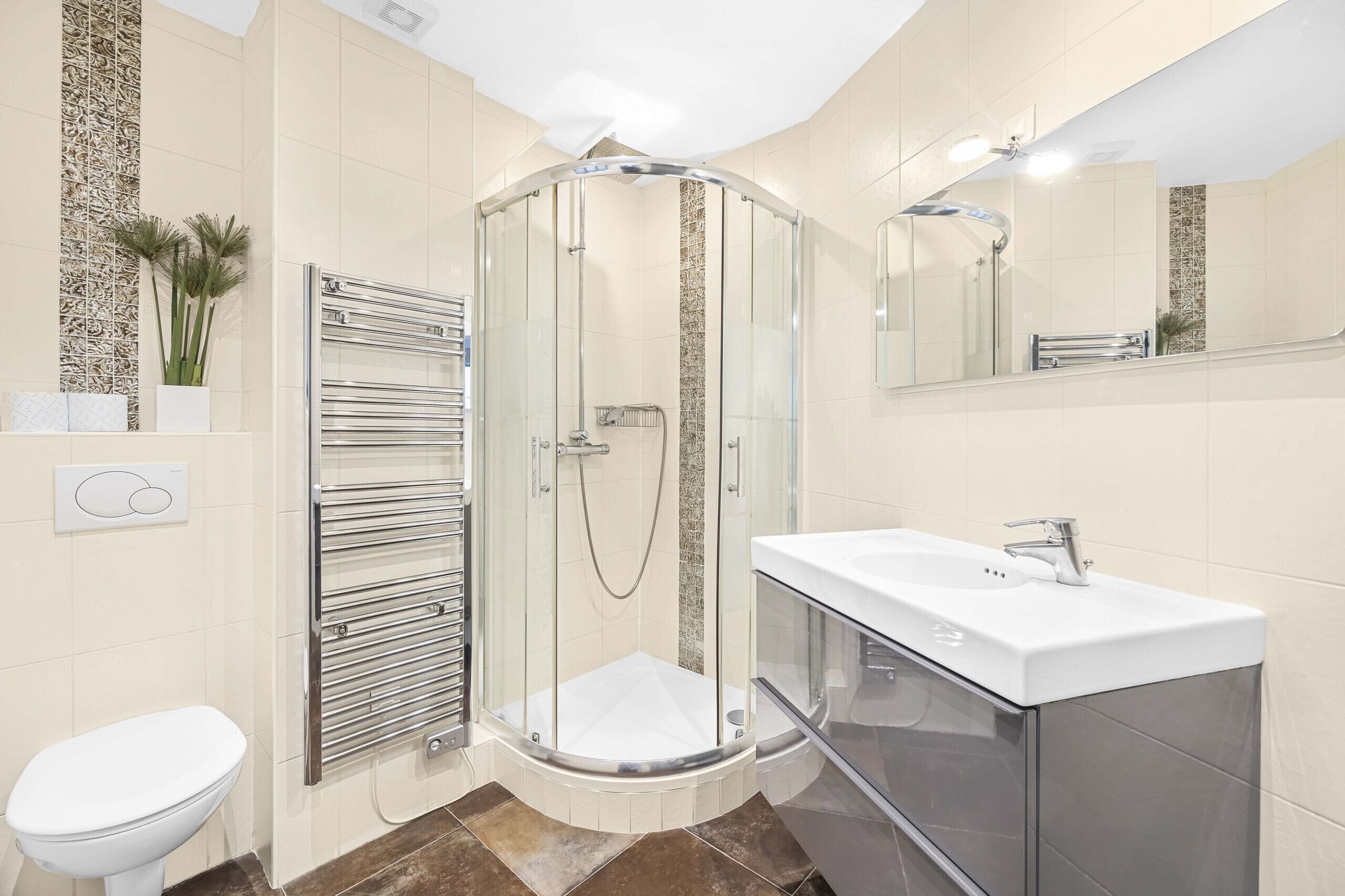 Un baño moderno con ducha envuelta en vidrio, inodoro blanco y tocador con lavamanos.