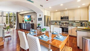 Una cocina amplia con electrodomésticos modernos, un comedor con mesa de madera para cuatro personas y una sala de estar acogedora con chimenea.