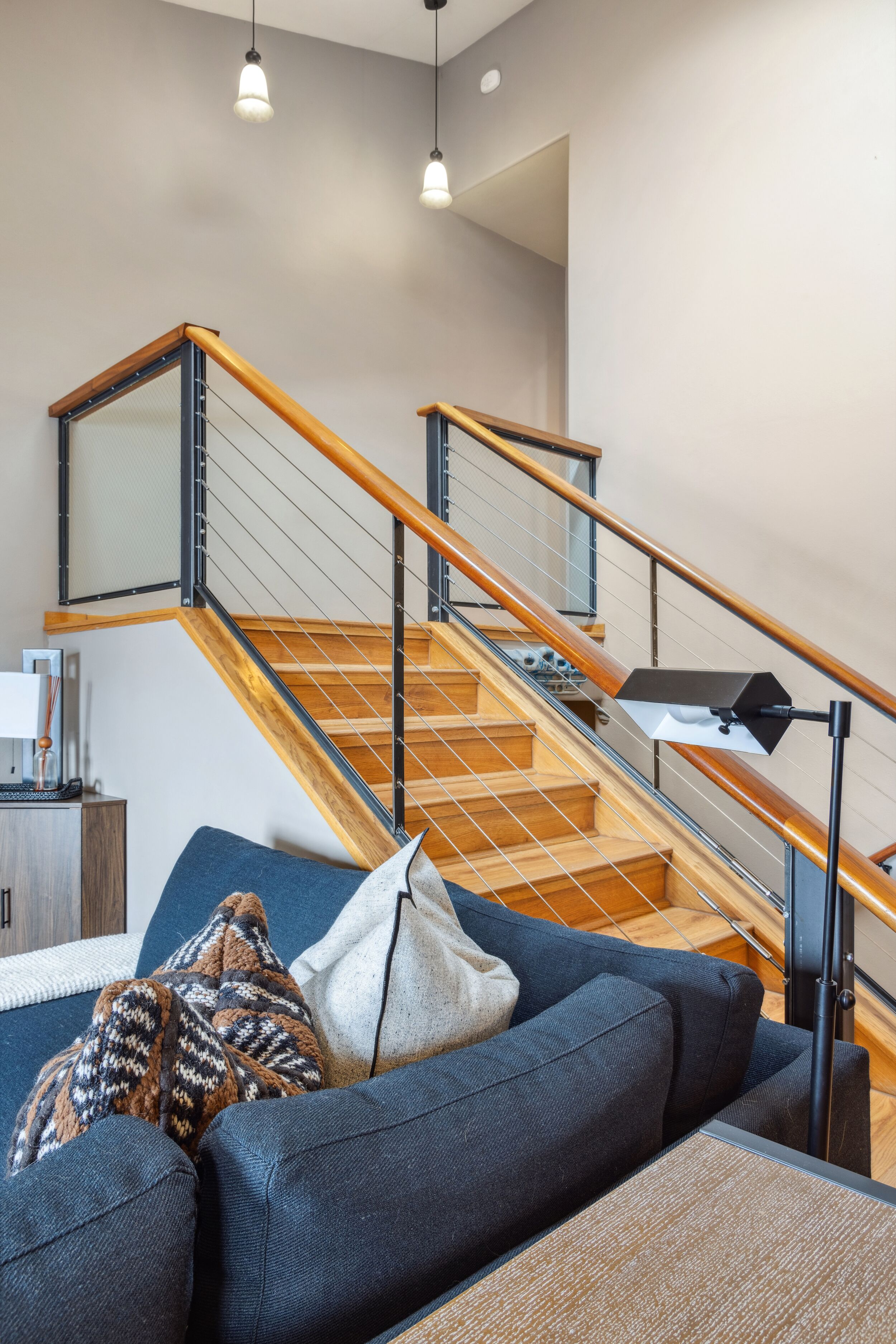 Un salon moderne avec un escalier en bois, un canapé et une lampe.