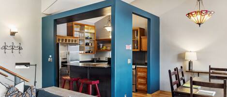 Een compacte leefruimte met kitchenette, een eethoek en een zithoek met een bank en stoelen.