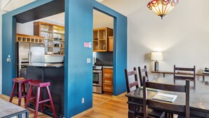 Une cuisine moderne avec des meubles en bois, un réfrigérateur et un coin repas comprenant une table et des chaises.