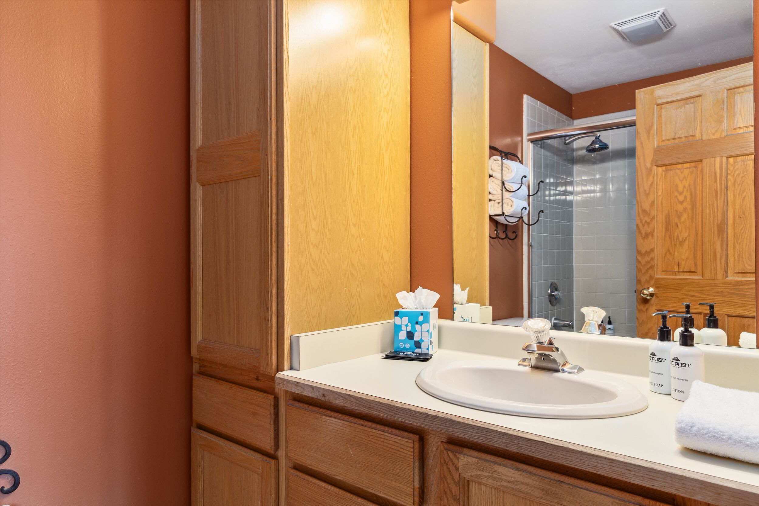 A bathroom with a wooden vanity, a sink, and a mirror.