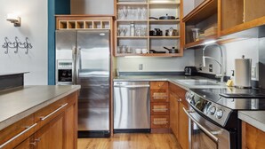 Une cuisine moderne dotée d’appareils électroménagers en acier inoxydable, de meubles en bois et d’étagères intégrées.