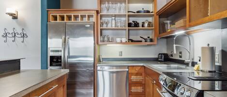 Una cocina moderna con electrodomésticos de acero inoxidable, armarios de madera y estanterías empotradas.