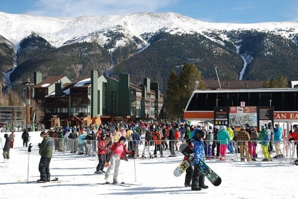 Une station de ski animée, avec des montagnes enneigées et des bâtiments visibles au loin.