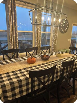 A dining area with a checkered tablecloth, black chairs, a pumpkin centerpiece, and a wall clock. - 3000 sq ft West Omaha home.  Perfect for wedding parties or families with kids! (Bennington)