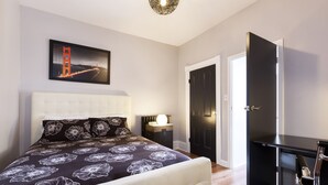 Un dormitorio con cama, mesita de noche, escritorio y puerta.
