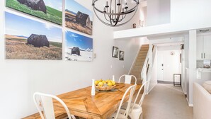 A dining area with a wooden table, white chairs, and a chandelier. - Outpost: Balsam Lodge A6 (Wilson)