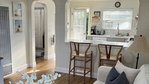 A modern living room with a white sofa, a wooden coffee table, and a ceiling fan. -  COZY BEACH HOUSE plus  GUEST HOUSE 
each unit 2 adults  PET FRIENDLY (Santa Cruz)