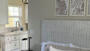 A bedroom with a bed, bedside table, and a view of the kitchen. -  COZY BEACH HOUSE plus  GUEST HOUSE 
each unit 2 adults  PET FRIENDLY (Santa Cruz)