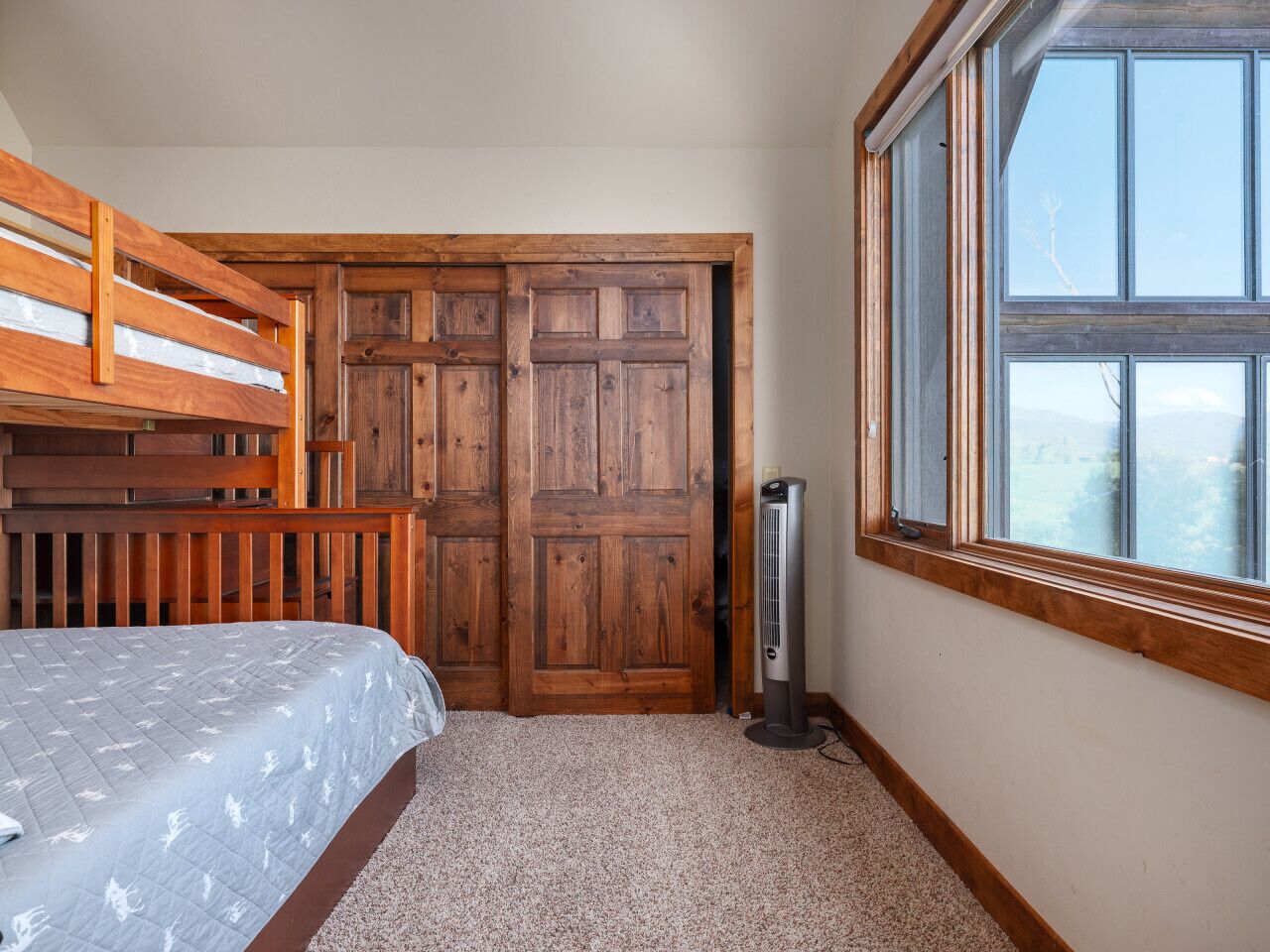 Une chambre avec un lit superposé, une armoire en bois, un radiateur et une fenêtre donnant sur un beau paysage.