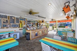 A restaurant with a bar area, tables, and chairs.