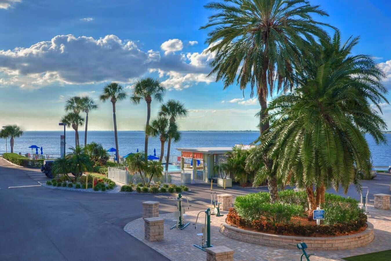 A beachfront property with palm trees, a pool area, and a view of the ocean.