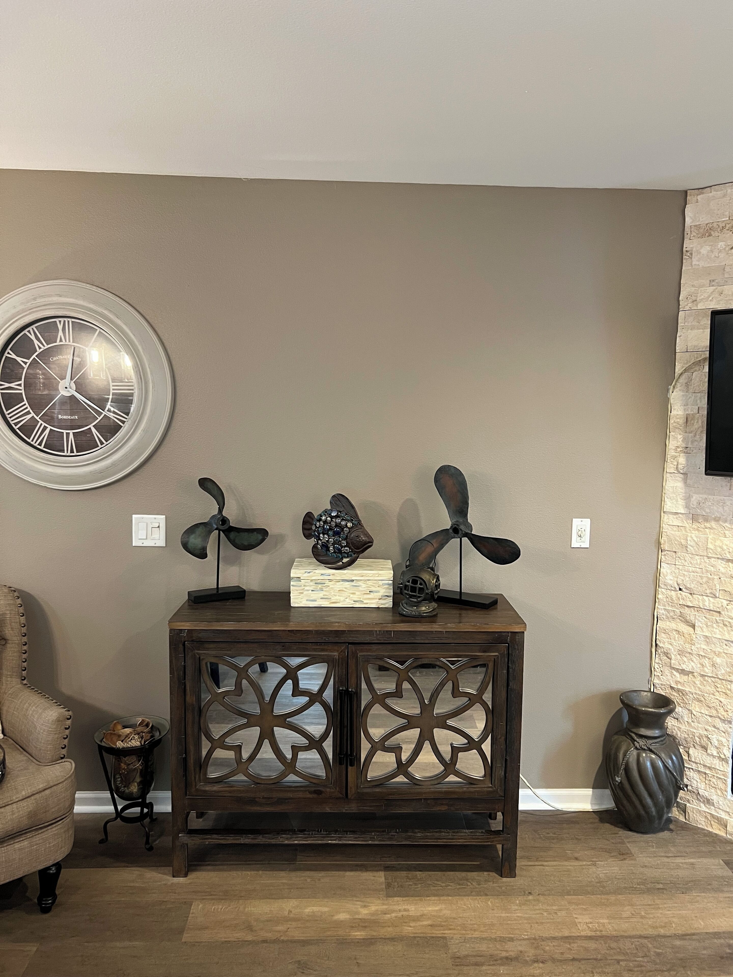A living room with a dark wooden console table, a round wall clock, and decorative fish sculptures.