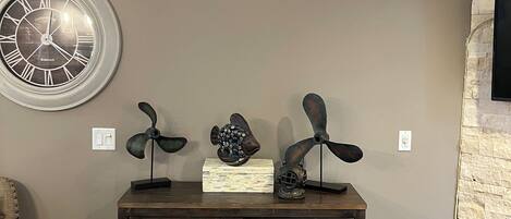 A living room with a dark wooden console table, a round wall clock, and decorative fish sculptures.
