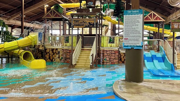 An indoor water park with slides, a pool, and a sign indicating pool capacity. -  Lake Life Luxury, Lake Geneva, Short Walk To Downtown, Pool View Upgraded Suite (Lake Geneva)