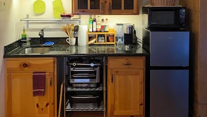 A compact kitchen with wooden cabinets, a built-in oven, a microwave, and a refrigerator. - Cozy quite private Aspen Studio  (Aspen)